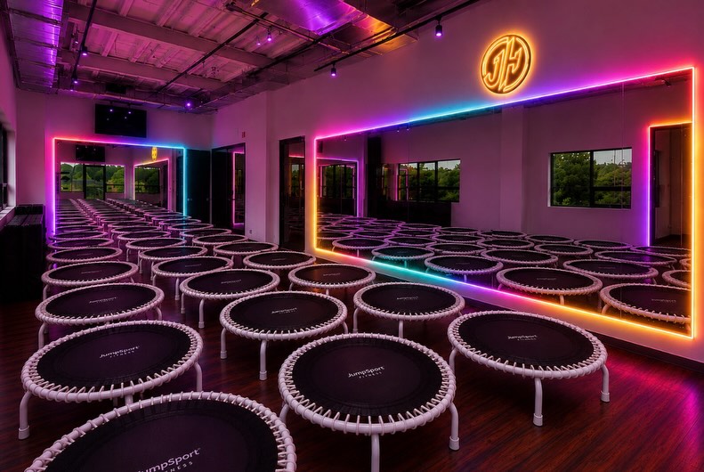The JumpHaus studio at The Fitness Loft with rows of rebounders and rainbow-lit mirrors